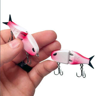 Two red and white BFS fishing lures with treble hooks held in a person's hand against a white background.